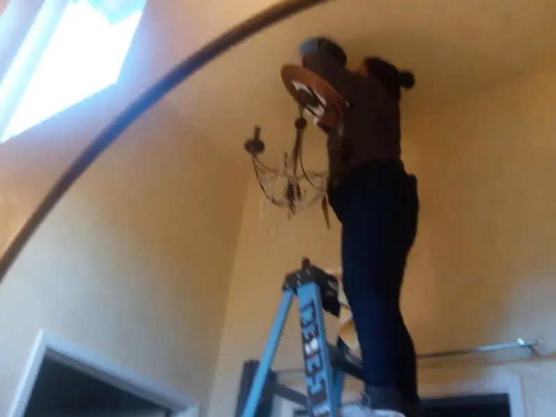 Electrician installing a chandelier in a Salem residence